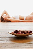 Fragrant potpourri in wooden bowl with woman in underwear in background