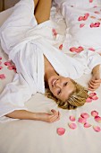 Frau entspannt sich im Bett auf Blütenblättern