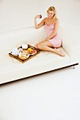 Young woman eating breakfast in living room