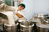 Frau füllt Milch in Container in einer Grossküche