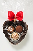 A chocolate heart with pralines and a red bow
