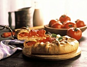 Tomatentarte mit einer Schale frischer Tomaten im Hintergrund