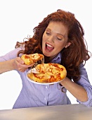 Junge Frau will gerade in ein Stück Pizza beissen