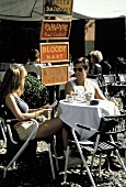 Menschen in Sommerkleidung am Tisch eines Strassencafes