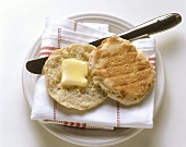 An English muffin with Butter on a Plate