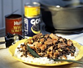 Bohnen-Wurst-Eintopf mit Reis auf Teller; Konservendosen