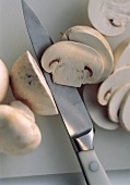 A Knife Slicing White Button Mushrooms