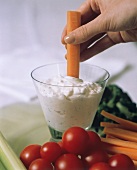 Hand Dipping a Carrot Stick into Dip