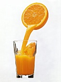 Orange Juice Pouring From Orange Half into a Glass