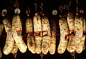 Toskanische Salamis hängen an Haken in einem Markt