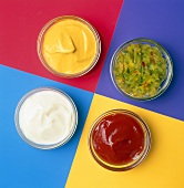 Assorted Condiments in Four Glass Bowls on Colored Squares