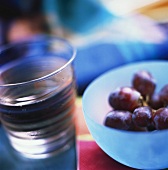 Glass of Water and a Bowl of Red Grapes