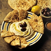 Hummus mit Oliven und Pita Chips auf Teller