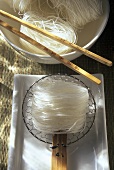 Asiatische Reisnudeln in Schale und auf Sieb