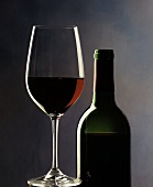 Ein Glas Rotwein neben Rotweinflasche
