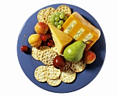 Cracker, Käse und frisches Obst auf blauem Teller