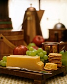 Cheddar Cheese with Crackers and Fruit on a Cutting Board