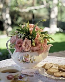 Sommerlicher Tisch im Freien mit Tee, Keksen und Rosen
