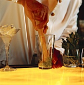 Barkeeper zerreibt Minzeblätter im Glas