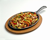 Beef, Onions and Peppers in Fajita Pan on a Wooden Board