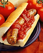 A sausage in a piece of baguette with tomato ketchup