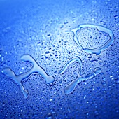 'H2O' mit Wassertropfen auf Glasscheibe geschrieben