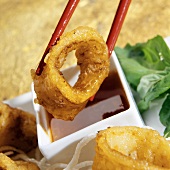 Chopsticks Holding Fried Calamari Over Ginger Soy Sauce