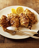 Chicken breasts with almond crust and lemons on plate