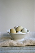 Fresh eggs in white bowl on cloth