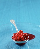 Pomegranate Seeds in a Ladle with Juice on Blue