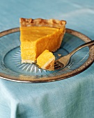 A slice of pumpkin pie with piece on fork