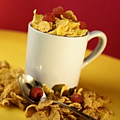 Cornflakes with raspberries in and beside cup