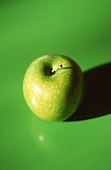 Ein Granny Smith Apfel auf grünem Untergrund