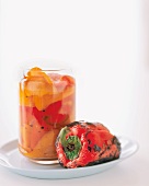 A Whole Roasted Red Pepper with a Jar of Roasted Peppers