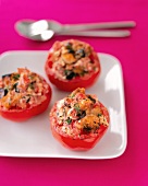 Three baked stuffed tomatoes on white plate