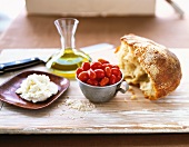 Stillleben mit Brot, Kirschtomaten, Olivenöl und Ricotta