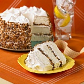 A slice of caramel layer cake with the rest of the cake in the background