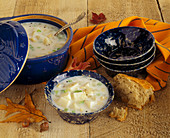 Clam Chowder in a Pot and in a Bowl with Bread and Autumn Leaves