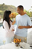 Couple with glasses of sparkling wine by swimming pool