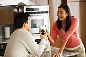 Young couple clinking glasses of red wine in kitchen