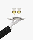 A Gloved Hand Holding a Silver Tray with Two Glasses of White Wine