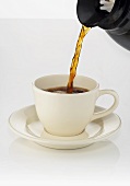 Kaffee aus Kanne in Tasse gießen