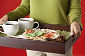 A Woman Carrying a Tray of Holiday Cookies and Coffee