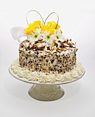 A Cake with White Frosting and White and Milk Chocolate Ribbons and Pieces