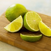 Whole and Sliced Limes on a Wooden Board, Close Up