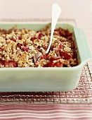 Strawberry Crisp in a Green Baking Dish with a Spoon