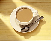 Milchkaffee in weisser Tasse mit Löffel
