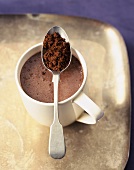 A Cup of Hot Cocoa on a Tray with Spoonful of Cocoa Powder