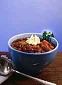 A bowl of chili with blue background