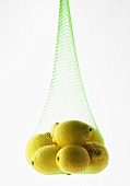 Fresh Lemons Hanging in Green Netting on White Background